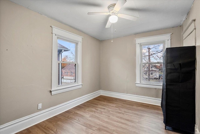 spare room featuring a ceiling fan, light wood-style floors, and baseboards