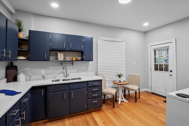 kitchen featuring blue cabinetry, open shelves, light wood-style flooring, range with electric stovetop, and a sink