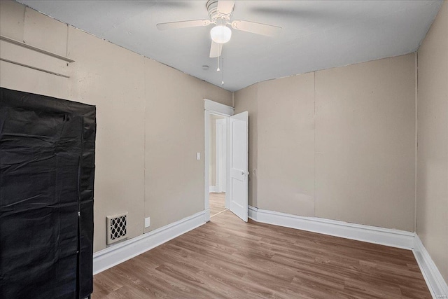 empty room with visible vents, baseboards, a ceiling fan, and wood finished floors