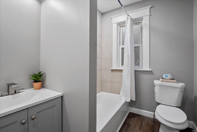 full bath with toilet, wood finished floors, vanity, baseboards, and shower / bathtub combination