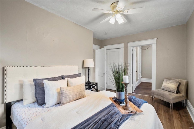 bedroom featuring a ceiling fan, wood finished floors, baseboards, and a textured ceiling