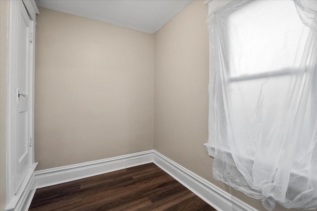 unfurnished room featuring baseboards and dark wood-style flooring