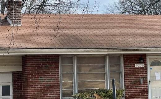 exterior details featuring brick siding and a shingled roof