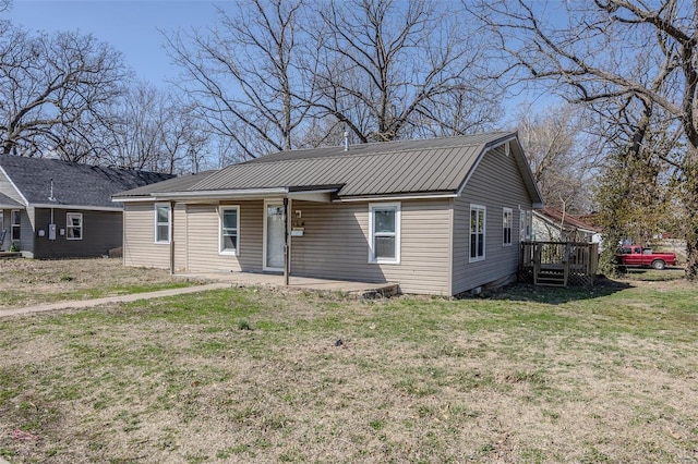 view of front of property featuring metal roof and a front lawn