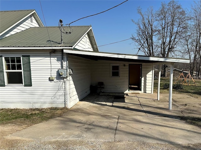 view of side of property with a carport, driveway, and metal roof