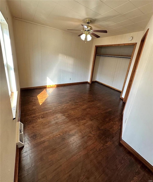 unfurnished bedroom featuring a ceiling fan, dark wood-style floors, a closet, and baseboards