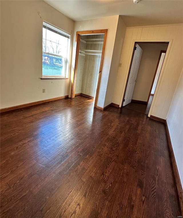 unfurnished bedroom featuring a closet, baseboards, and dark wood-style flooring