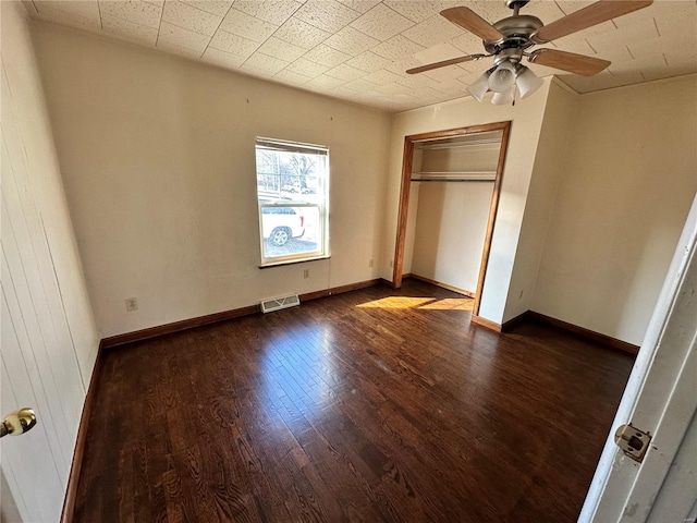 unfurnished bedroom featuring visible vents, dark wood finished floors, a closet, baseboards, and ceiling fan