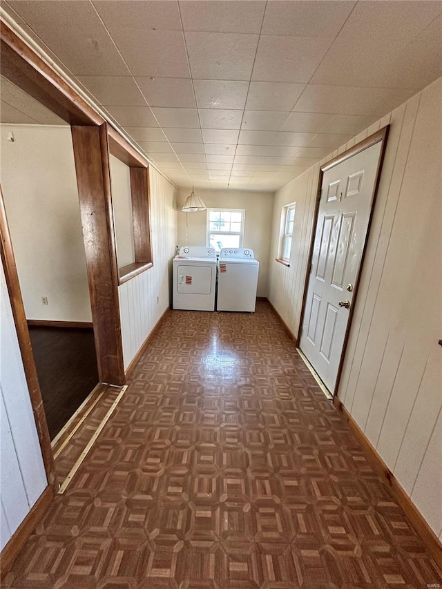 laundry area featuring laundry area, wooden walls, separate washer and dryer, and baseboards