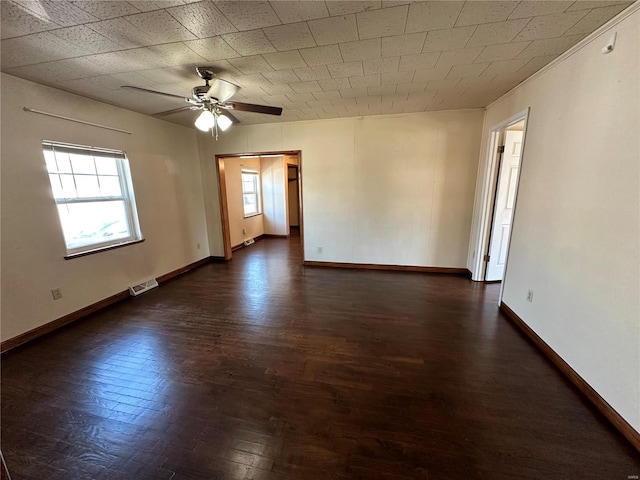 unfurnished room with visible vents, a ceiling fan, baseboards, and dark wood-style flooring