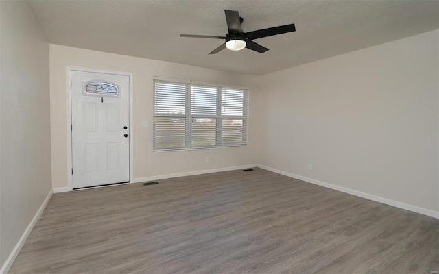 foyer entrance with baseboards, a textured ceiling, a ceiling fan, and wood finished floors