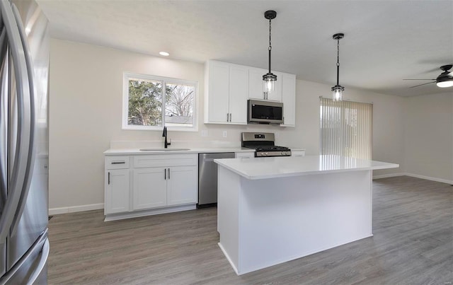 kitchen featuring a ceiling fan, a sink, stainless steel appliances, light wood-style floors, and light countertops