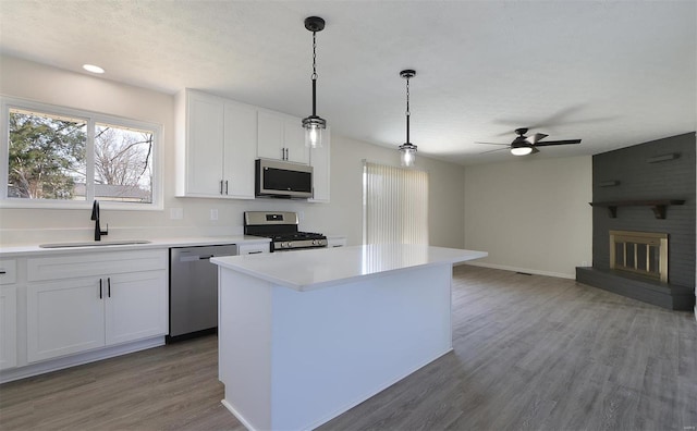 kitchen with light wood-type flooring, light countertops, stainless steel appliances, a ceiling fan, and a sink