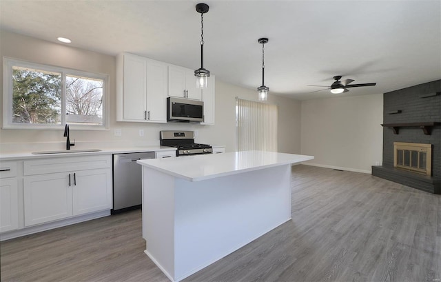 kitchen with light countertops, light wood-style flooring, stainless steel appliances, a ceiling fan, and a sink