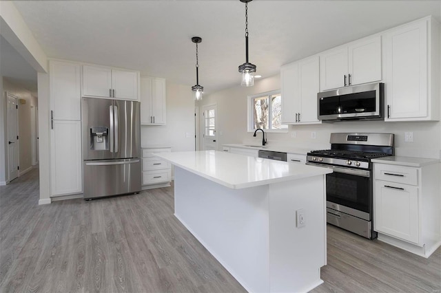 kitchen with a kitchen island, stainless steel appliances, light wood-type flooring, and light countertops