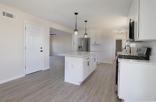 kitchen featuring visible vents, a kitchen island, light wood-type flooring, appliances with stainless steel finishes, and white cabinetry