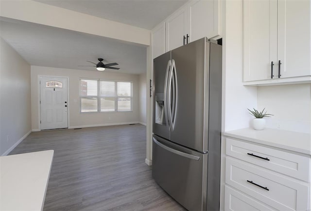 kitchen featuring ceiling fan, stainless steel fridge with ice dispenser, light countertops, light wood-style flooring, and white cabinets