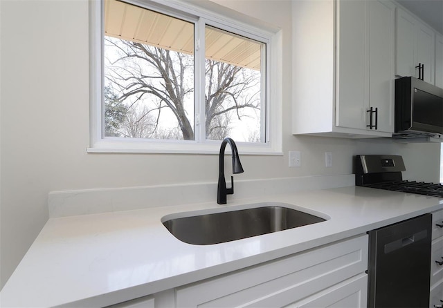 kitchen with light countertops, dishwashing machine, black microwave, and a sink