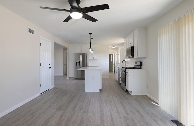 kitchen with visible vents, ceiling fan, stainless steel appliances, white cabinets, and a center island