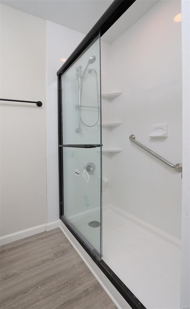 full bath with a shower stall, wood finished floors, and baseboards