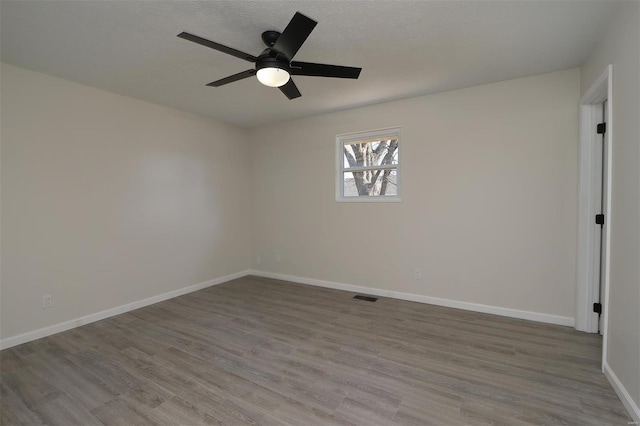 unfurnished room with visible vents, a textured ceiling, wood finished floors, baseboards, and ceiling fan