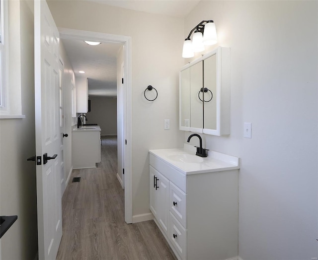 bathroom with visible vents, baseboards, wood finished floors, and vanity