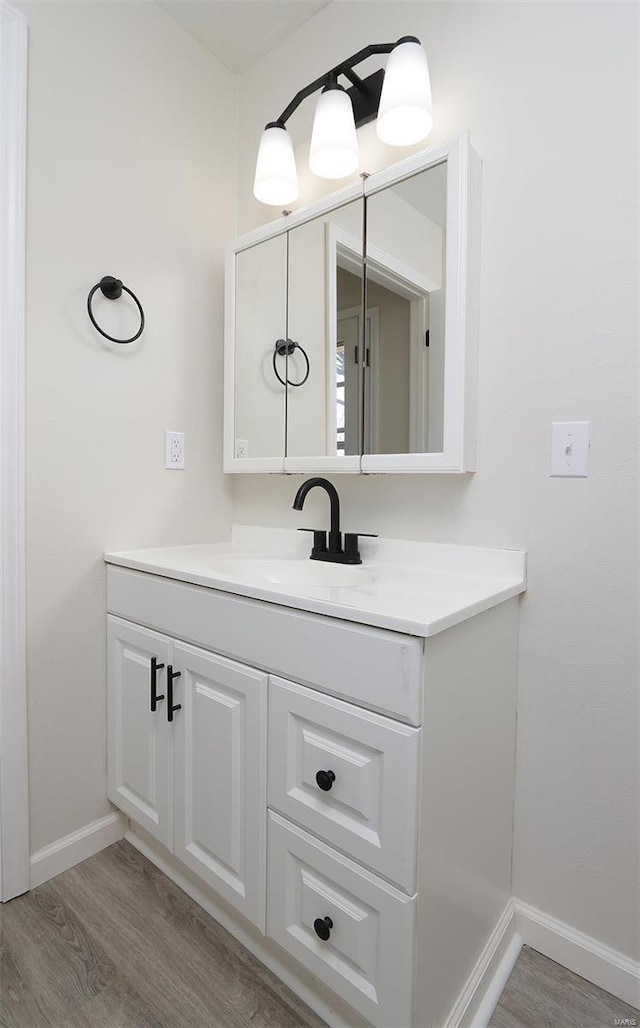 bathroom with vanity, wood finished floors, and baseboards