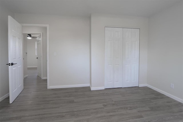 unfurnished bedroom featuring a closet, baseboards, and wood finished floors