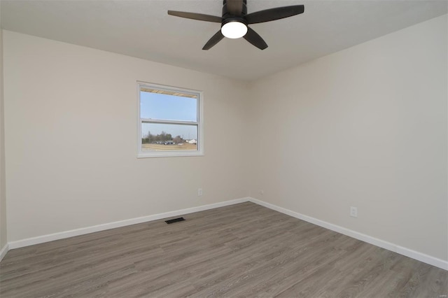 spare room featuring visible vents, baseboards, wood finished floors, and a ceiling fan