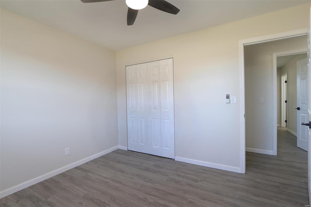 unfurnished bedroom with ceiling fan, a closet, baseboards, and wood finished floors