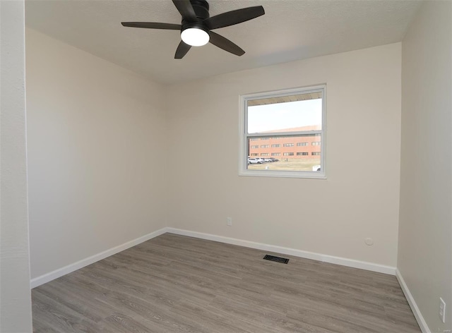 unfurnished room with visible vents, baseboards, wood finished floors, a textured ceiling, and a ceiling fan