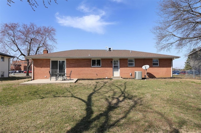 rear view of property with brick siding, central AC unit, a chimney, a yard, and a patio area