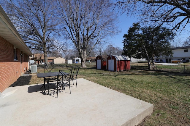 view of patio with outdoor dining space, an outbuilding, central AC unit, fence, and a shed