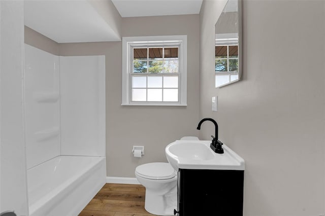 bathroom with toilet, wood finished floors, washtub / shower combination, baseboards, and vanity