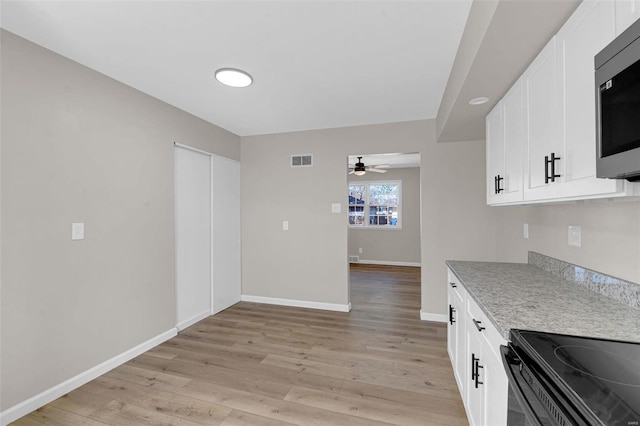 kitchen featuring stainless steel microwave, ceiling fan, light wood-style flooring, and visible vents