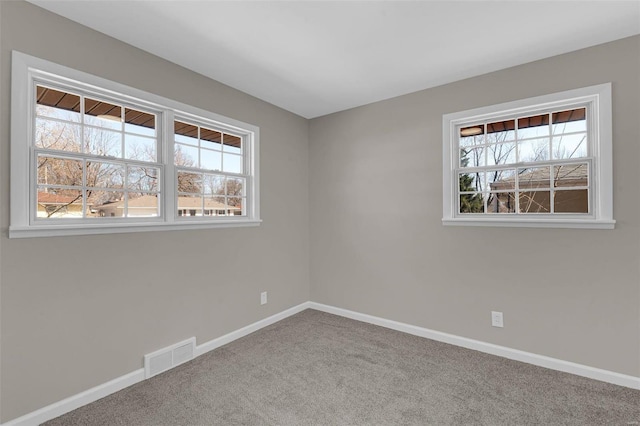 carpeted spare room with visible vents and baseboards