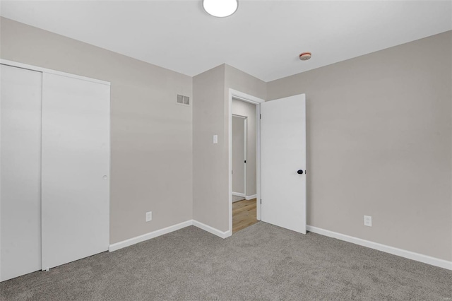 unfurnished bedroom with carpet, visible vents, a closet, and baseboards