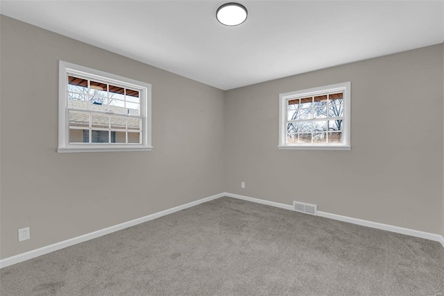 carpeted empty room featuring visible vents and baseboards