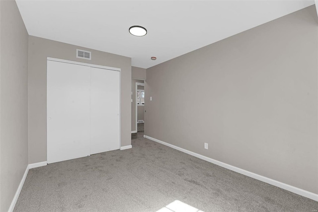 unfurnished bedroom featuring a closet, visible vents, baseboards, and carpet floors