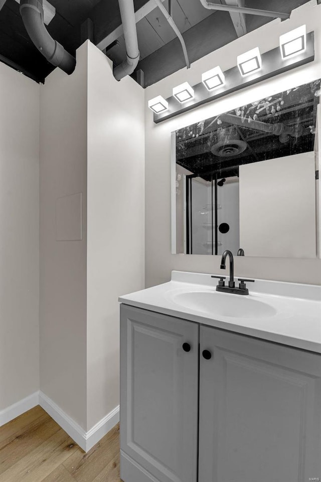 bathroom with vanity, wood finished floors, and baseboards