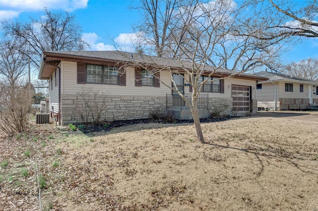 single story home with an attached garage, central AC unit, and driveway