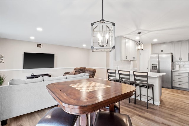 dining space with recessed lighting, light wood-type flooring, and an inviting chandelier