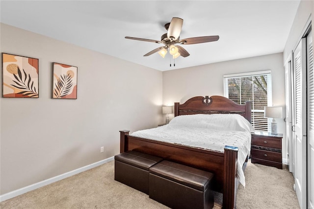 bedroom featuring a closet, baseboards, light carpet, and a ceiling fan