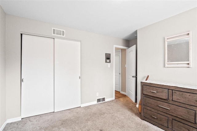 bedroom featuring visible vents, baseboards, light colored carpet, and a closet