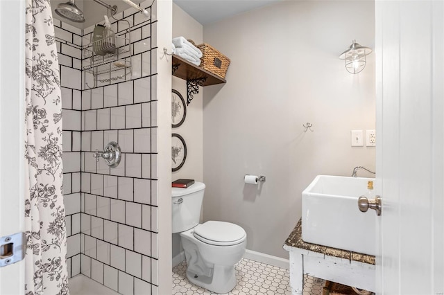 bathroom featuring toilet, baseboards, tile patterned floors, a sink, and tiled shower