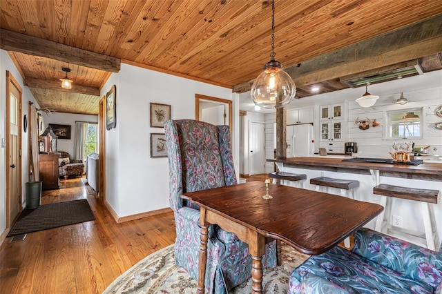 dining space with baseboards, beamed ceiling, wood finished floors, and wooden ceiling