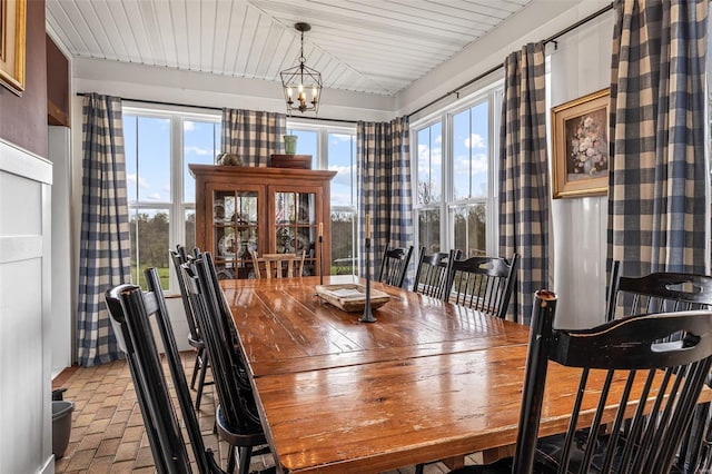 dining space with brick floor and a notable chandelier