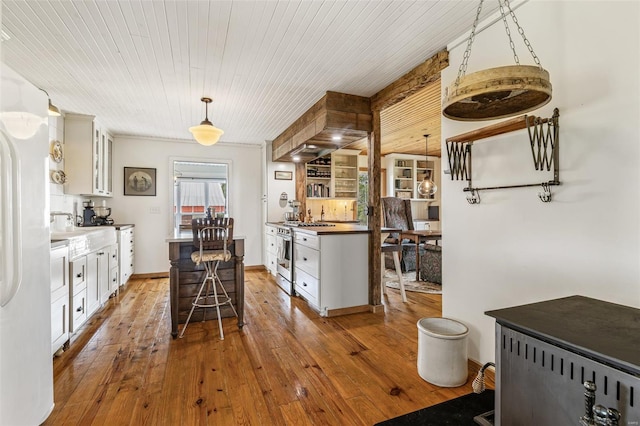 kitchen with a breakfast bar, glass insert cabinets, stainless steel range with gas stovetop, white cabinets, and hardwood / wood-style floors