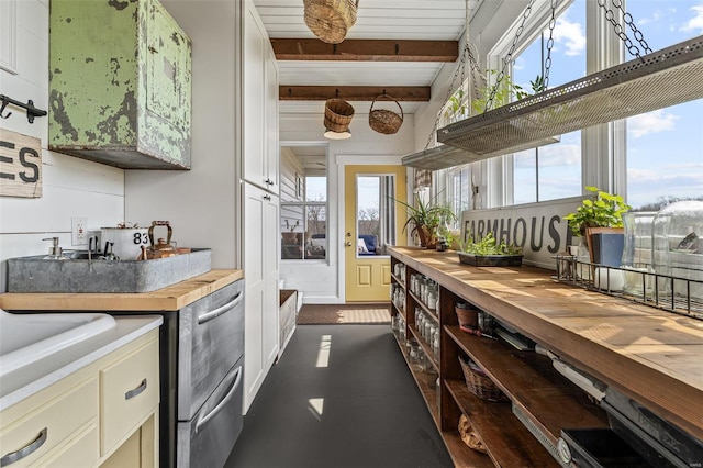 kitchen featuring a wealth of natural light, beamed ceiling, and butcher block counters