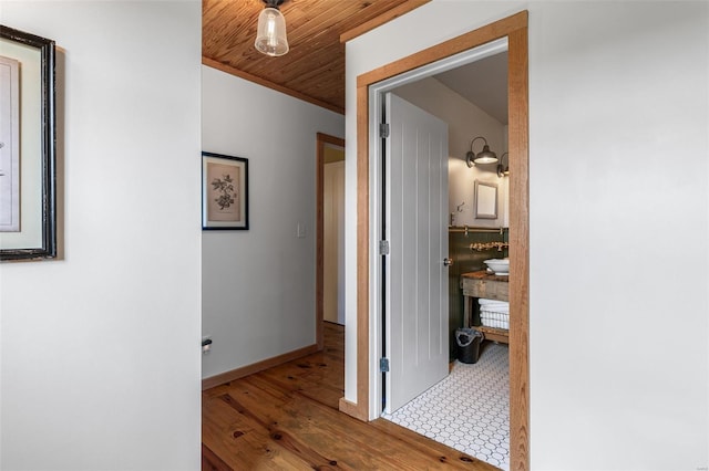 hallway with baseboards, crown molding, wood finished floors, and wooden ceiling
